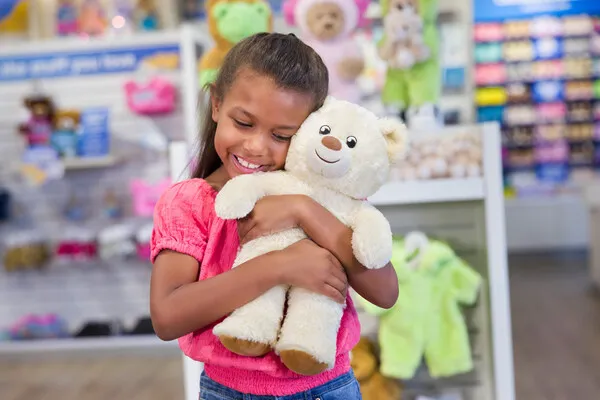 A child hugging a teddy bear for Build-A-Bear Workshop&#x27;s National Teddy Bear Day Limited Time $9 Bear Offer