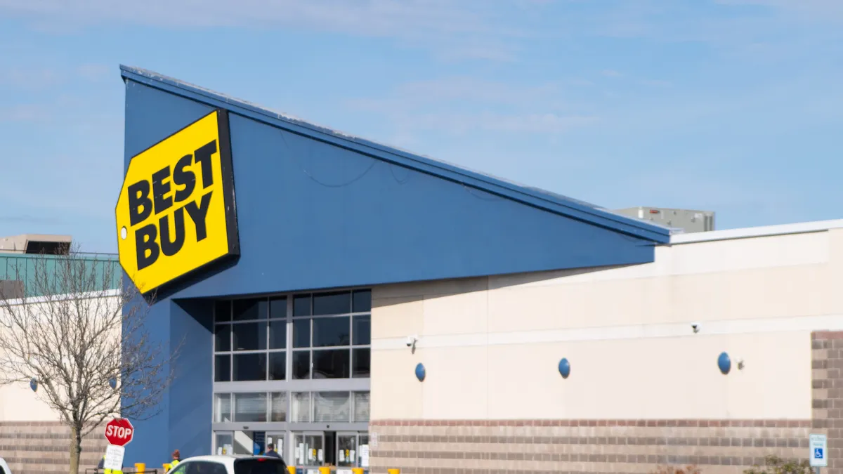 A bright yellow sign against a blue roof says "Best Buy" in bold black letters.