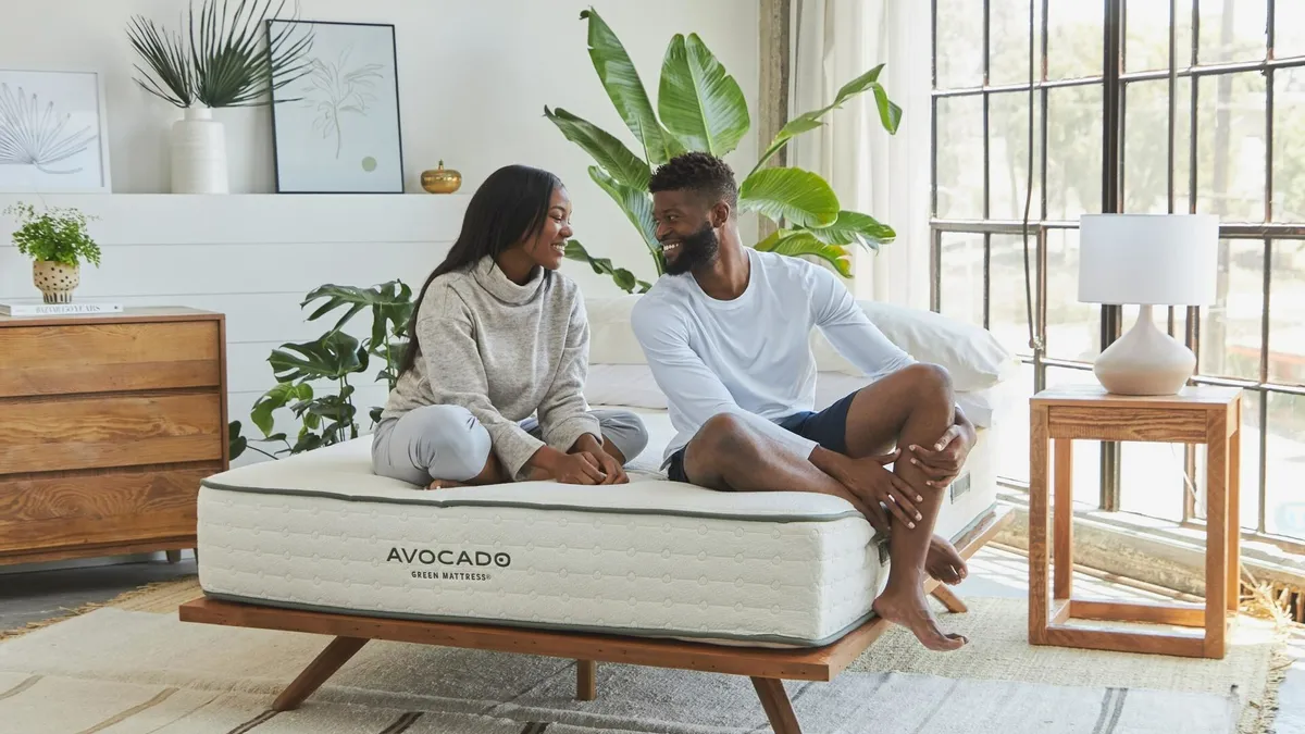 Two people sit on an Avocado mattress