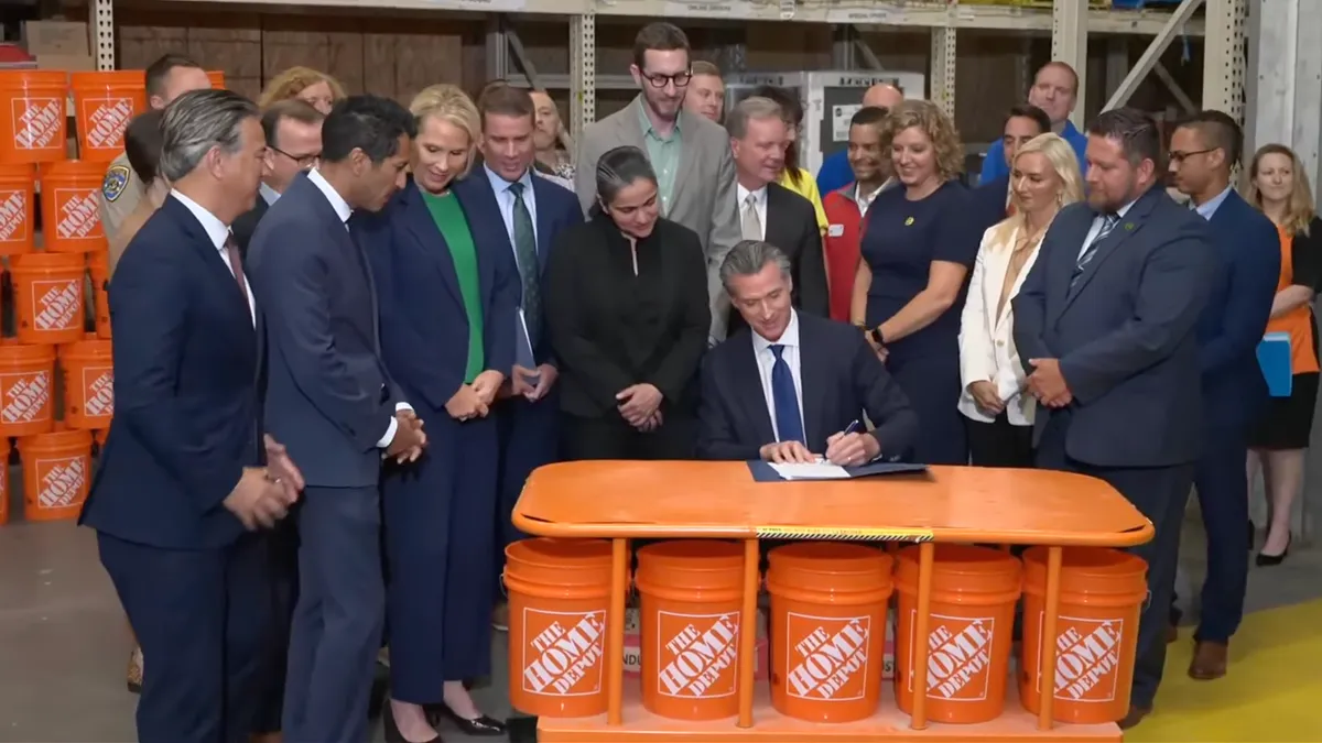 A group of people crowd around a person in a suit in tie signing papers.