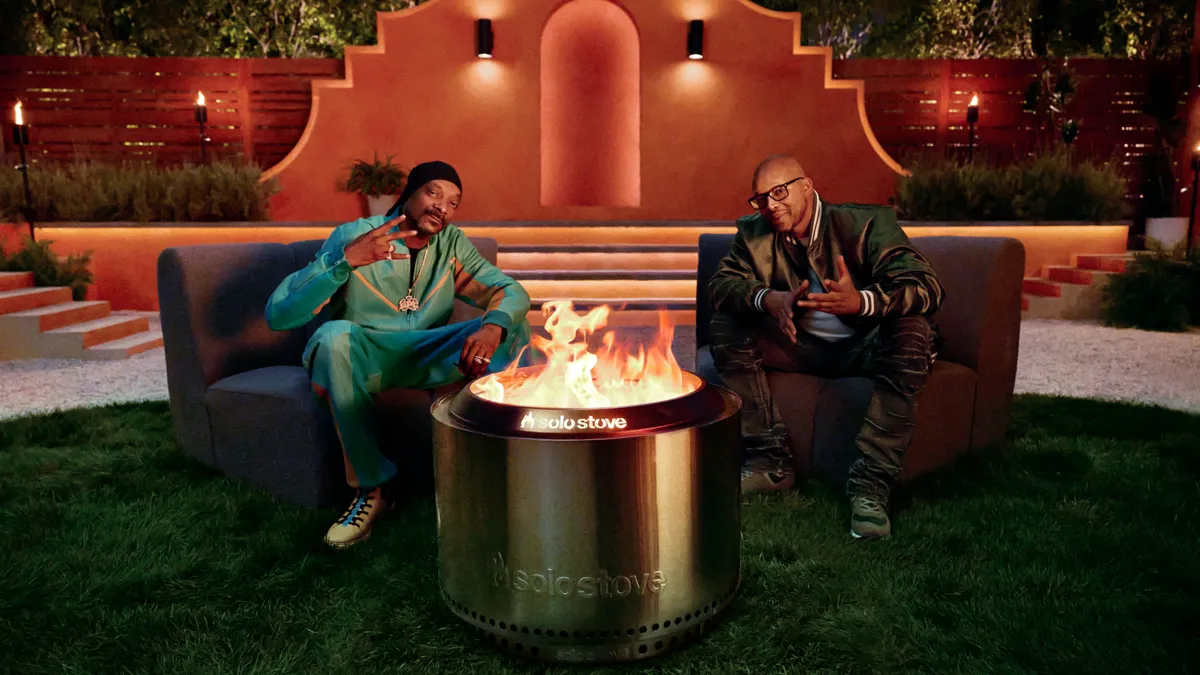 Snoop Dogg and Warren G. sit around a Solo Stove at night.